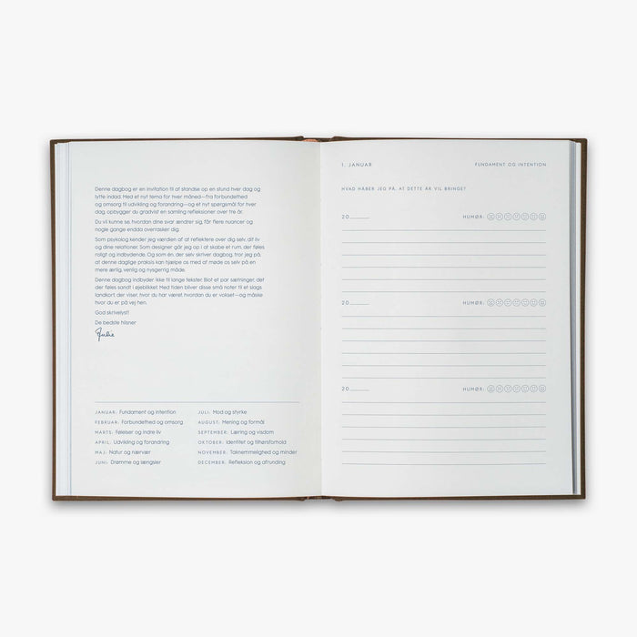 Open book from our Three Year Journal (Treårsdagbogen) with short description of the purpose of the book and the daily prompts on a white background