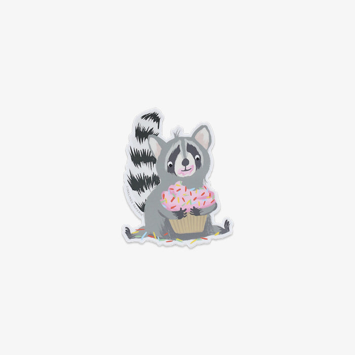 Vinyl sticker of a raccoon holding a cupcake on a white background